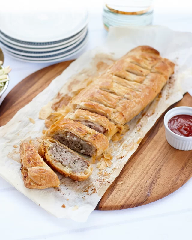 Serving a crowd this summer? Try making this King Sized Posh Sausage Roll using our Pork & Apple or Cumberland Sausages!Save the recipe for later ⬇️INGREDIENTS
1 onion, finely diced
4 rashers of British Sausage Ham & Bacon Co Traditional Smoked Streaky Bacon, diced
6 British Sausage Co Pork & Apple Sausages
375g all-butter puff pastry (rolled to approx. 25cm x 50cm wide) or use two thawed puff pastry sheets joined together
Egg, beaten (for pastry)METHOD
1. Preheat oven to 220°C (200°C fan-forced).
2. Heat oil in a frying pan over medium heat. Add the onion and bacon. Cook until the onion is soft, and the bacon is nicely browned. Set aside to cool slightly.
3. Remove the skins from the sausages and place the sausage meat into a large bowl.
4. Add the cooled onion and bacon mixture to the sausage meat and mix well to combine.
5. Lay out the puff pastry on a clean surface. Spoon the sausage mixture in a long, even line down the centre of the pastry.
6. Fold the pastry over the filling to enclose, pressing the edges together to seal. Use a fork to crimp the seam if desired.
7. Place seam-side up (for a rustic look) on a lined baking tray. Brush the top with a beaten egg. Then, using a sharp knife, make a few diagonal slits across the top to allow steam to escape during baking.
8. Bake for 30–35 minutes or until the pastry is golden and puffed, and the filling is cooked through.
9. Rest for 5 minutes before slicing. Serve warm or at room temperature.