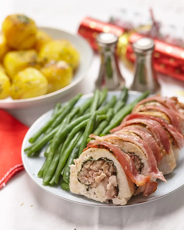 Want to to add some sausages to your classic Christmas meal? Try this delicious sausage stuffing featuring our Cumberland Sausages!Save the recipe for later ⬇️INGREDIENTS
For Meat & Stuffing:1 large chicken or turkey breast butterflied and flattened (ask your butcher or see below for how to)
3 British Sausage Co. Thick Cumberland or Thick Pork Sausage (casings removed)
2 rashers British Smoked Streaky Bacon, diced
1 small brown onion (finely diced)
1 or 2 leaves of cavolo nero, stem removed (or spinach leaves)
1 tsp fresh thyme, finely chopped (or ½ tsp dried)
Salt and pepper, to taste
Olive oil or butter, for fryingTo Wrap & Roast:4 to 6 rashers British Smoked Streaky Bacon (enough to cover the roll)
Butcher’s twine or toothpicks (optional)
Olive oil or melted butter, for brushingMETHOD
1. Make the Stuffing: Heat a drizzle of olive oil or butter in a frying pan over a low to medium heat. Add the finely diced onion and gently cook for 5 minutes or until translucent. Increase the pan to medium heat and add the thyme, diced bacon and sausages (breaking up the sausage filling with a wooden spoon) and sauté until all ingredients are golden (5–6 mins). Remove from heat and let cool.2. Stuff and Roll: Lay the prepared flattened butterflied breast on a board. Place a cavolo nero leaf or spinach leaves over most of the chicken breast, leaving 3cms uncovered along the longest side of the flattened breast.  Then spread the stuffing mixture down the centre of the meat. Carefully roll the breast over the stuffing, tucking in as you go to form a neat log. Tie or use toothpicks to secure log.3. Wrap in Bacon: Place the stuffed roll seam side down in the roasting pan and lay the bacon slices over the roll, tucking under and securing with toothpicks.4. Roast: Preheat oven to 180°C (160°C fan). Brush the roll with olive oil or melted butter and roast for 35 to 45, or until the internal temperature reaches 75°C and the bacon is golden and crisp. If needed, finish under the grill for 2–3 minutes to crisp the bacon further. Rest for 10 minutes before slicing.5. Serve: Slice into thick rounds and serve with roast veggies, greens and gravy.