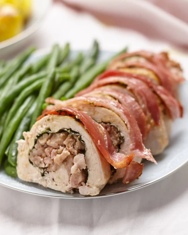 Looking to put on an Easter feast packed with your favourite British Sausage Co. products? This is the recipe for you!Our Bacon-wrapped Chicken Roulade with Sausage Stuffing combines our Cumberland Sausages and Smoked Streaky Bacon. Full recipe below ⬇️INGREDIENTS
For Meat & Stuffing:
1 large chicken or turkey breast butterflied and flattened
3 British Sausage Co. Thick Cumberland or Thick Pork Sausage (casings removed)
2 rashers British Smoked Streaky Bacon, diced
1 small brown onion (finely diced)
1 or 2 leaves of cavolo nero, stem removed (or spinach leaves)
1 tsp fresh thyme, finely chopped (or ½ tsp dried)
Salt and pepper, to taste
Olive oil or butterTo Wrap & Roast:
4 to 6 rashers British Smoked Streaky Bacon (enough to cover the roll)
Butcher’s twine or toothpicks (optional)
Olive oil or melted butter, for brushingMETHOD
1. Heat a drizzle of olive oil or butter in a frying pan over a low to medium heat. Add the finely diced onion and gently cook for 5 minutes or until translucent. Increase the pan to medium heat and add the thyme, diced bacon and sausages (breaking up the sausage filling with a wooden spoon) and sauté until all ingredients are golden (5–6 mins). Remove from heat and cool.2. Lay the prepared flattened butterflied breast on a board. Place a cavolo nero leaf over most of the chicken breast, leaving 3cms uncovered along longest side of the flattened breast. Spread the stuffing mixture down the centre. Carefully roll the breast over the stuffing, tucking in as you go to form a neat log. Tie or use toothpicks to secure log.3. Place stuffed roll seam side down in roasting pan and lay bacon slices over the roll, tucking under and securing with toothpicks.4. Preheat oven to 180°C (160°C fan). Brush the roll with olive oil or melted butter and roast for 35 to 45, or until the internal temperature reaches 75°C and the bacon is golden and crisp. If needed, finish under the grill for 2–3 minutes to crisp the bacon further. Rest for 10 mins before slicing.5. To serve, slice into thick rounds and serve with roast veggies, greens and gravy.#baconwrappedideas #easterrecipes #roastdinnerideas #chickenrouladerecipe #sausagestuffingrecipe
